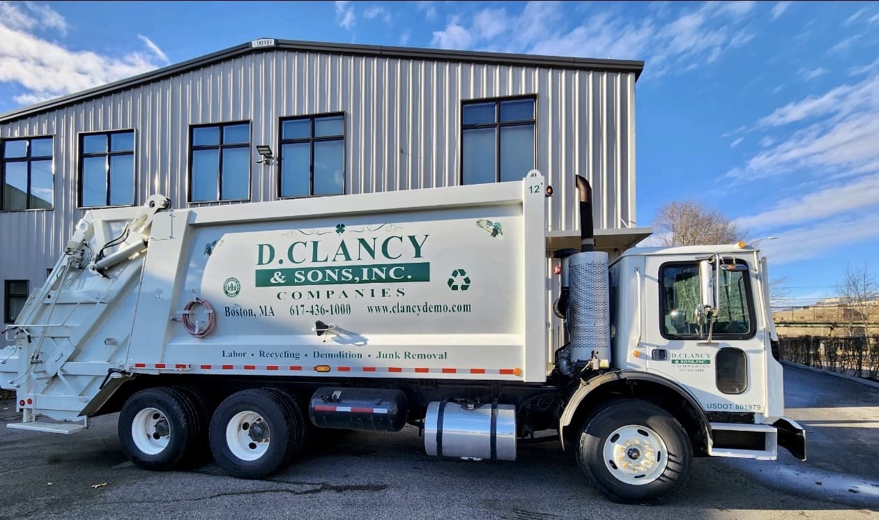 D. Clancy & Sons 30-yard compactor truck live-loading construction debris on a jobsite